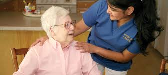 Caregiver smiling and comforting elderly woman at home.